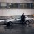 Mies seisoo auton vieressä sateessa.